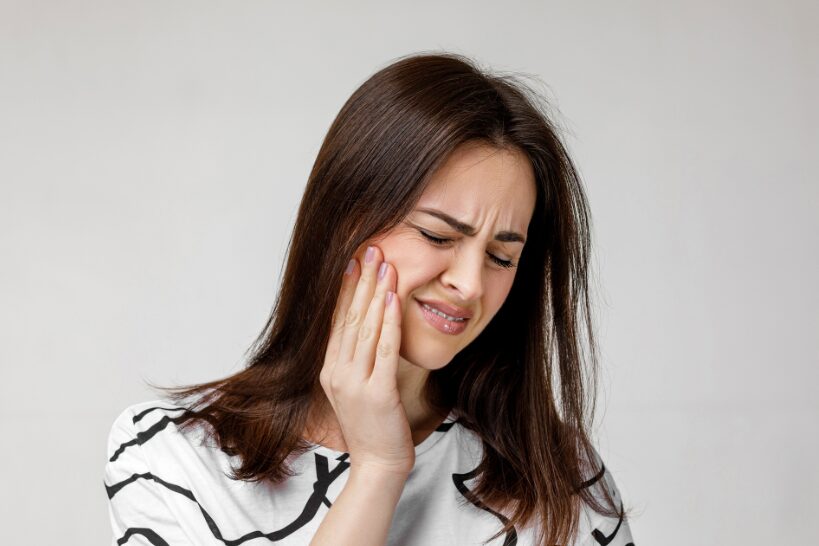Woman holding her cheeks in pain from a severe toothache needing an emergency dentist